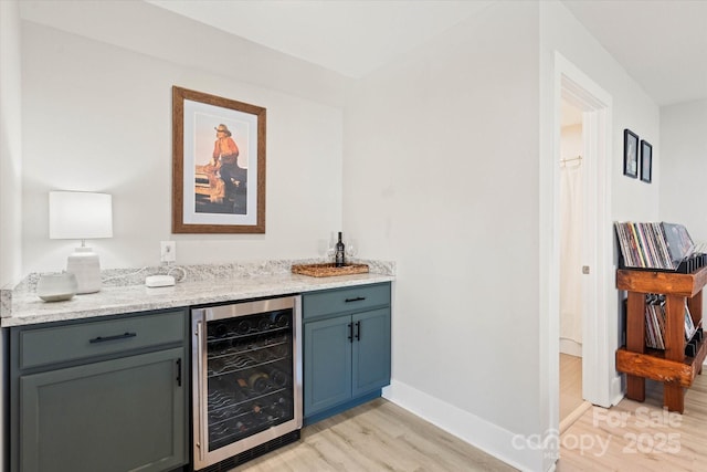 bar featuring wine cooler, light wood-type flooring, and light stone counters