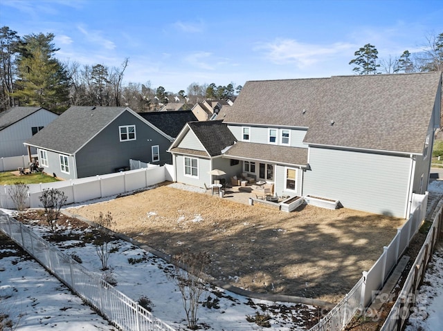 snow covered rear of property with a patio area