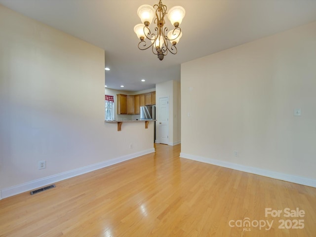 unfurnished living room featuring a chandelier and light hardwood / wood-style floors