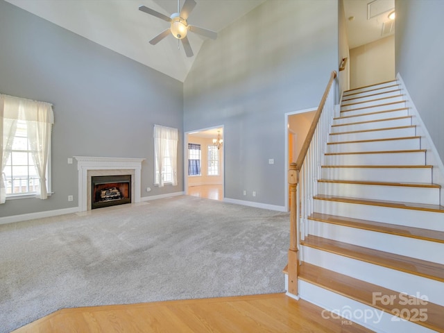 unfurnished living room featuring carpet, a wealth of natural light, high vaulted ceiling, and ceiling fan