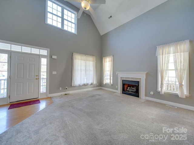 unfurnished living room with a high ceiling, light colored carpet, and ceiling fan