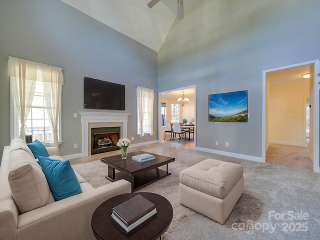 living room featuring light carpet, ceiling fan with notable chandelier, high vaulted ceiling, and a healthy amount of sunlight