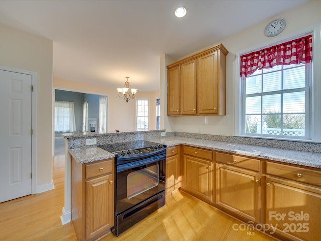 kitchen with electric range, light stone countertops, light hardwood / wood-style flooring, a notable chandelier, and kitchen peninsula