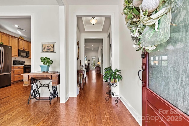 entrance foyer featuring a raised ceiling, wood finished floors, baseboards, and visible vents