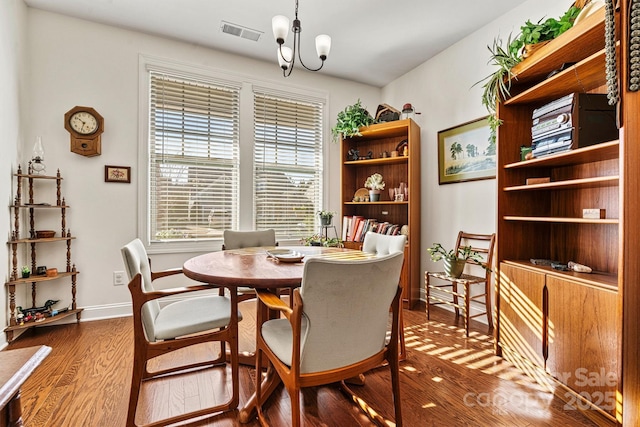 dining room with visible vents, baseboards, a notable chandelier, and wood finished floors