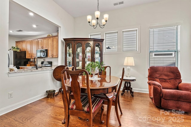 dining room featuring sink, a chandelier, and light hardwood / wood-style flooring