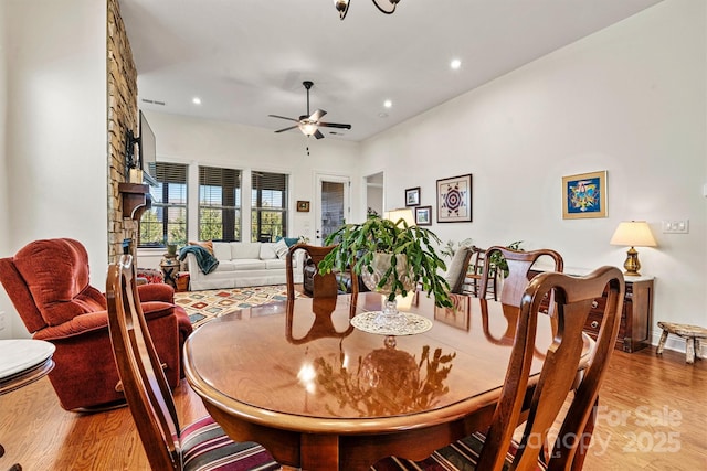 dining space with a stone fireplace, recessed lighting, light wood-type flooring, and a ceiling fan