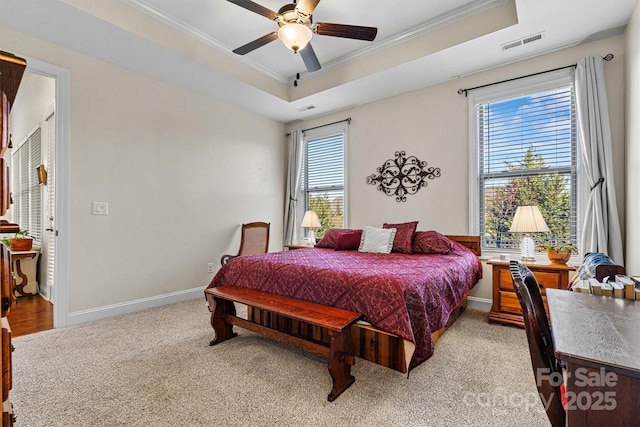 bedroom featuring ceiling fan, light carpet, multiple windows, and a tray ceiling