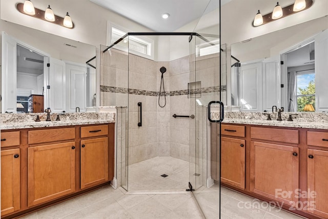 bathroom with a shower stall, a healthy amount of sunlight, and two vanities