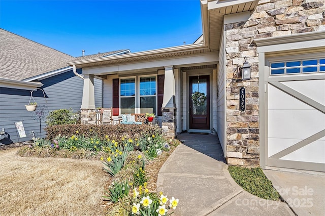 entrance to property with a garage, stone siding, and a porch