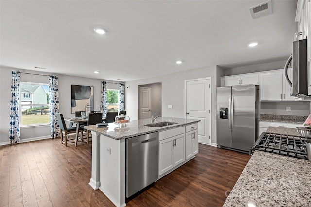 kitchen with white cabinets, a center island with sink, sink, appliances with stainless steel finishes, and light stone counters