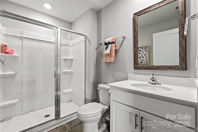 bathroom featuring vanity, toilet, and a shower with door