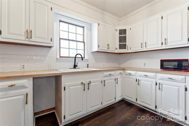 kitchen with white cabinets, dark hardwood / wood-style floors, crown molding, and sink