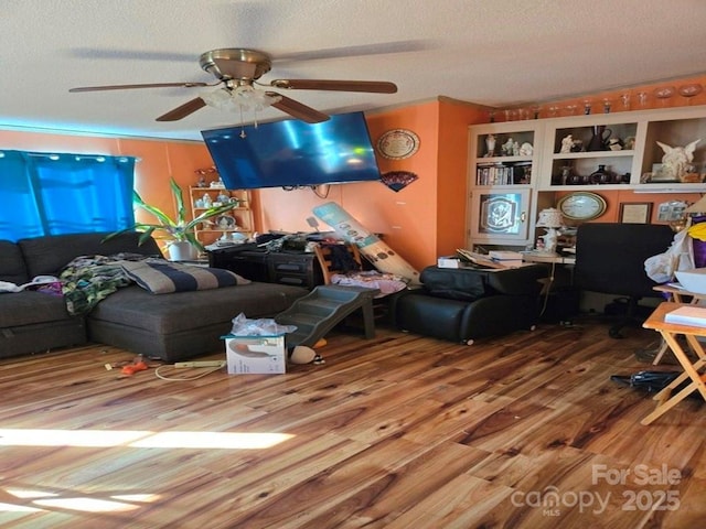 living room featuring wood-type flooring, a textured ceiling, and ceiling fan