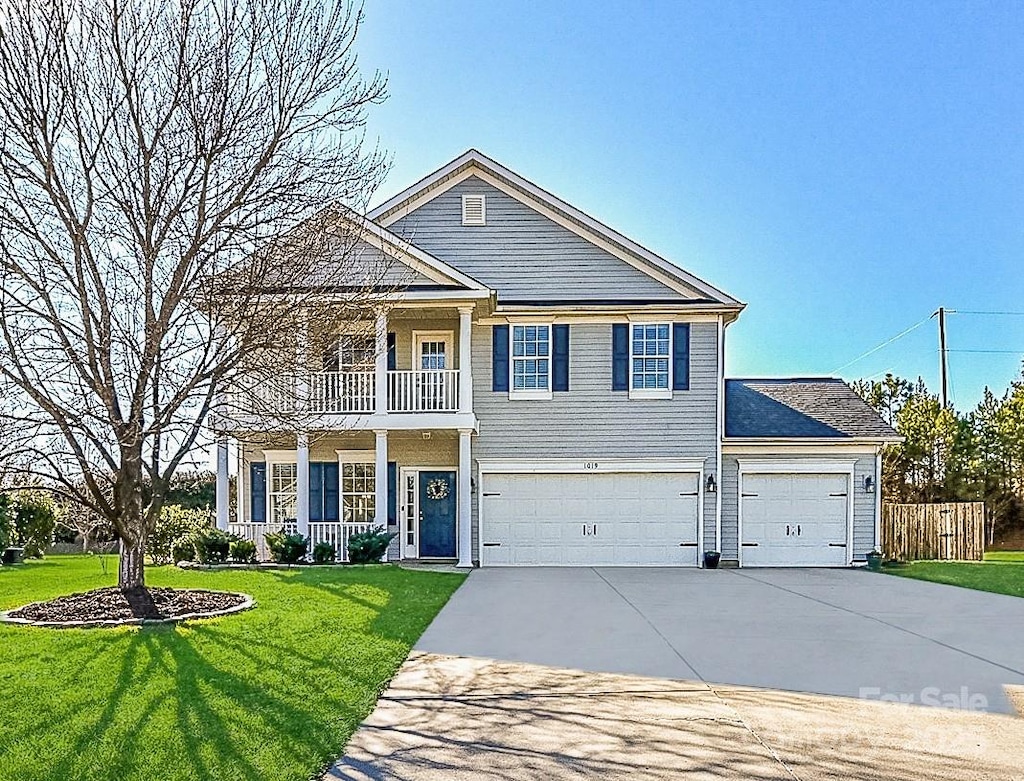 view of front of house with a porch, a garage, a balcony, and a front yard