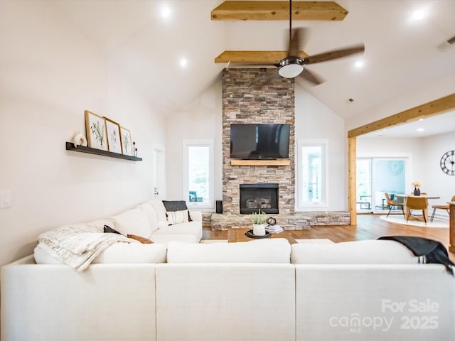 living room featuring a stone fireplace, ceiling fan, high vaulted ceiling, and a healthy amount of sunlight