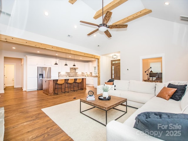 living room featuring beamed ceiling, ceiling fan, light wood-type flooring, and high vaulted ceiling