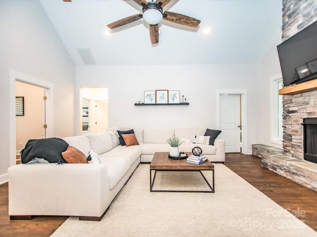 living room featuring hardwood / wood-style flooring, ceiling fan, a stone fireplace, and high vaulted ceiling