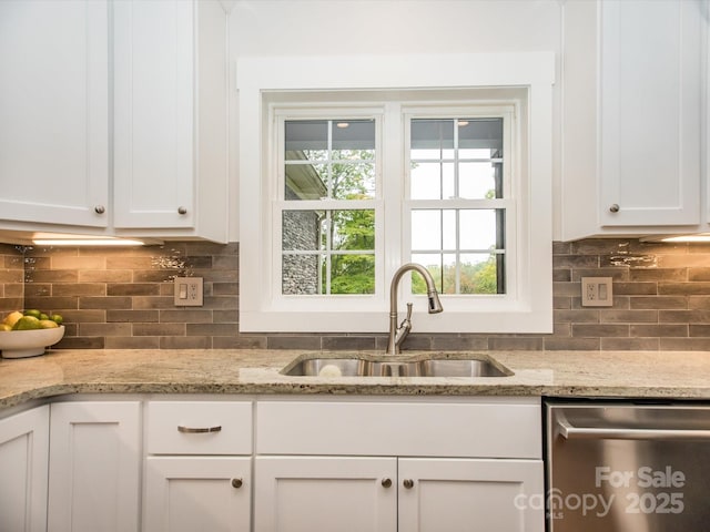 kitchen with dishwasher, white cabinetry, and sink