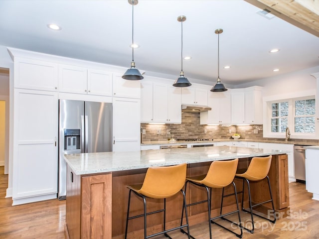 kitchen with pendant lighting, a large island, white cabinetry, and light hardwood / wood-style flooring