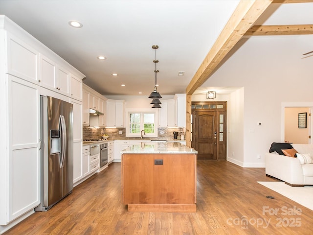 kitchen featuring appliances with stainless steel finishes, light stone counters, decorative light fixtures, hardwood / wood-style floors, and white cabinetry