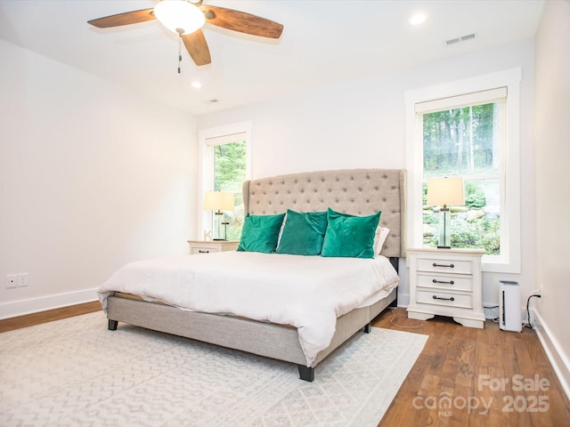 bedroom with multiple windows, hardwood / wood-style flooring, and ceiling fan