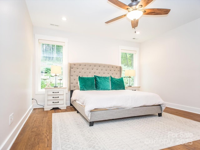 bedroom featuring ceiling fan, wood-type flooring, and multiple windows