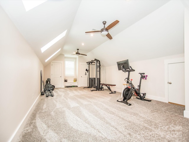 exercise area with ceiling fan, vaulted ceiling with skylight, and light colored carpet