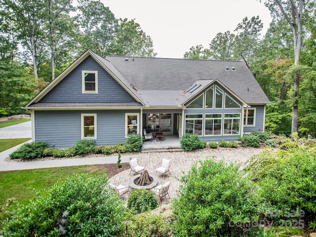 rear view of property featuring a patio area and an outdoor fire pit