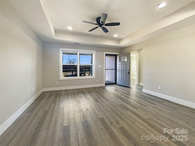 interior space with ceiling fan, dark hardwood / wood-style flooring, and a raised ceiling