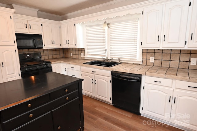 kitchen with light wood-type flooring, backsplash, sink, black appliances, and white cabinets