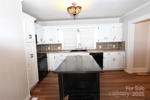 kitchen featuring a center island, sink, white cabinets, black appliances, and ornamental molding