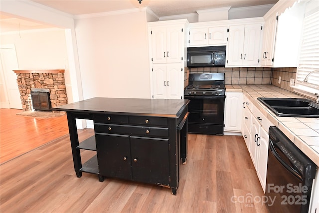 kitchen featuring backsplash, black appliances, sink, tile counters, and white cabinetry