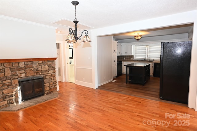 kitchen featuring hardwood / wood-style floors, a kitchen island, pendant lighting, and black appliances