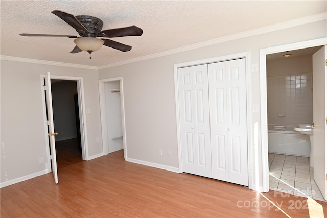 unfurnished bedroom featuring ensuite bathroom, ceiling fan, light wood-type flooring, and crown molding