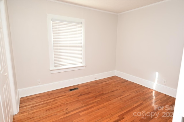 spare room featuring wood-type flooring and crown molding