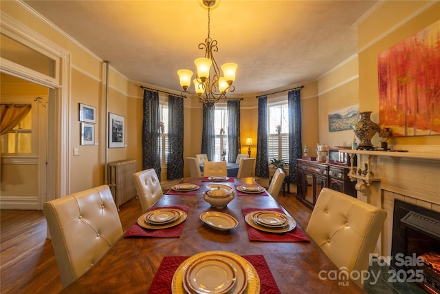 dining space with radiator, hardwood / wood-style floors, a chandelier, and ornamental molding