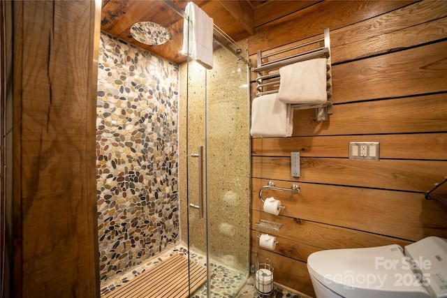 bathroom with toilet, a shower with shower door, and wooden walls