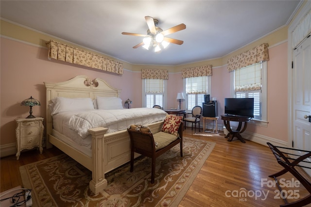 bedroom featuring a closet, hardwood / wood-style flooring, ceiling fan, and crown molding