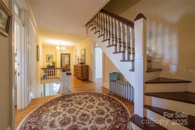 stairway with hardwood / wood-style flooring, radiator heating unit, and an inviting chandelier