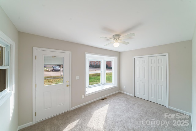 interior space with light carpet, a closet, and ceiling fan