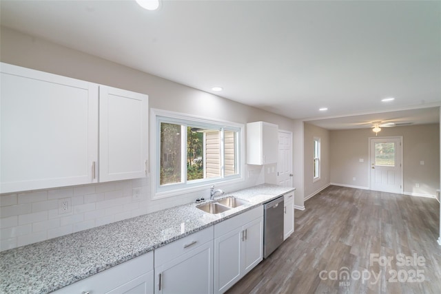 kitchen with stainless steel dishwasher, decorative backsplash, white cabinets, and sink