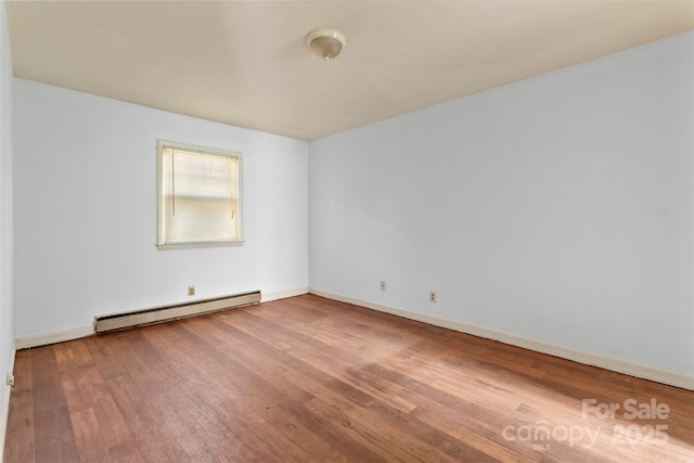 spare room with a baseboard radiator and hardwood / wood-style flooring