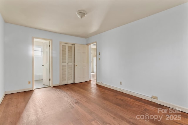 unfurnished bedroom featuring wood-type flooring and connected bathroom