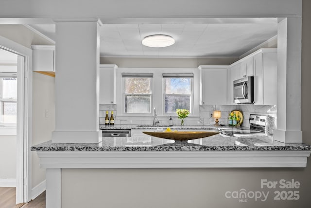 kitchen with backsplash, sink, appliances with stainless steel finishes, white cabinets, and light stone counters