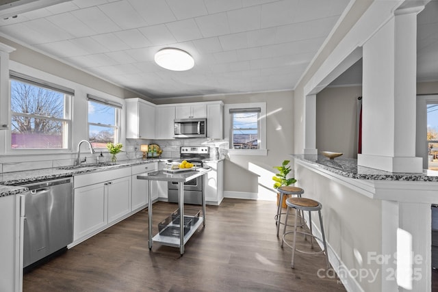 kitchen with light stone counters, sink, white cabinetry, and appliances with stainless steel finishes