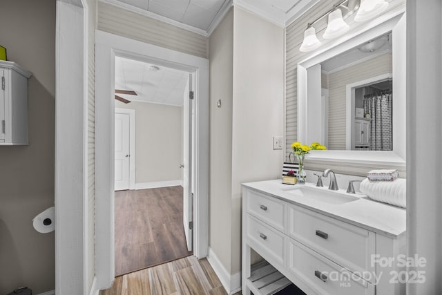 bathroom featuring ceiling fan, vanity, crown molding, and hardwood / wood-style flooring