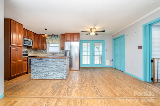 kitchen featuring appliances with stainless steel finishes, french doors, crown molding, light hardwood / wood-style floors, and hanging light fixtures