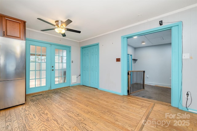 unfurnished room featuring french doors, light hardwood / wood-style floors, ceiling fan, and crown molding