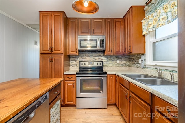 kitchen featuring sink, stainless steel appliances, butcher block countertops, light wood-type flooring, and ornamental molding